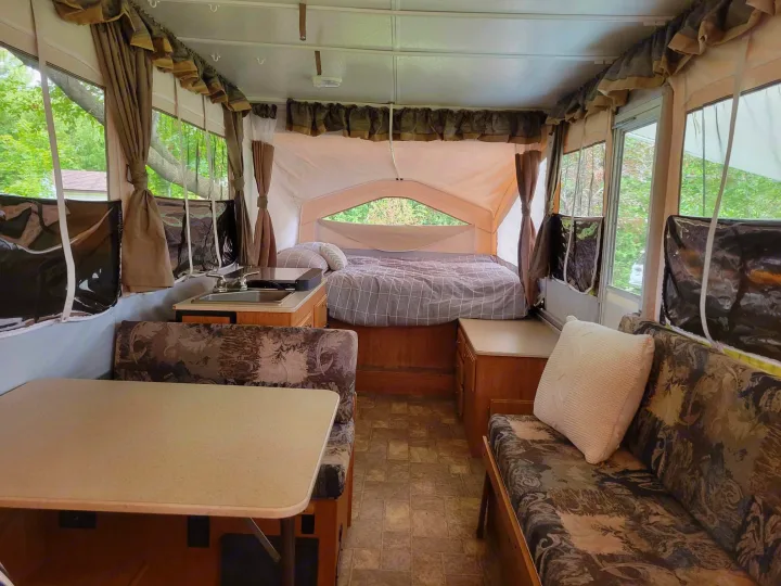 Interior of an RV rental pop-up camper: comfy bed, dinette, and compact kitchen. Perfect for travel adventures.. Forest River Flagstaff M.A.C. 2011