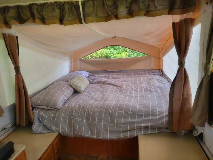 Cozy pop-up camper interior with a comfy bed & window view of nature. Ideal for your next RV rental!. Forest River Flagstaff M.A.C. 2011