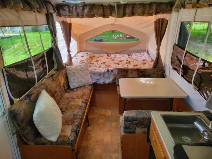 Cozy pop-up rv rental interior featuring a bed, dinette, and small kitchen with sink.. Forest River Flagstaff M.A.C. 2011