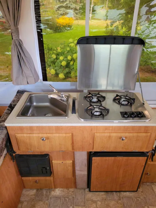 RV rental interior: A compact kitchen area with a stainless steel sink, 3-burner stove, and Dometic fridge.. Forest River Flagstaff M.A.C. 2011
