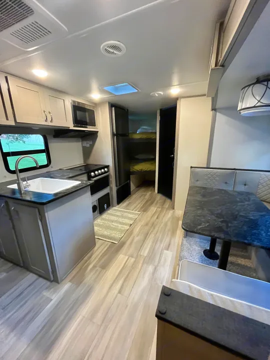 Modern RV rental interior: well-equipped kitchen, comfy dining area, and bunk beds. Perfect for road trips.. Forest River Tracer 2022