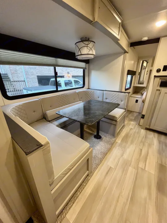 RV rental: Light-colored U-shaped dinette with a black table and window view, ideal for dining inside the vehicle.. Forest River Tracer 2022