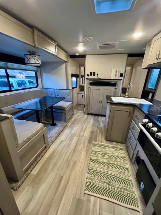 Bright travel trailer RV rental interior with modern kitchen, dinette, and wood-look floors.. Forest River Tracer 2022