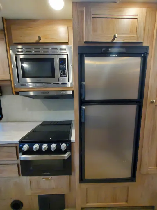 Well-equipped RV rental kitchen features a stainless microwave, Dometic fridge, and Furrion stove/oven.. Forest River Sunseeker 2019