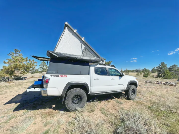 White Toyota Tacoma with GFC pop-top camper, ideal for RV rental adventures & overland camping in nature.. Toyota Tacoma TRD Off-Road 2023