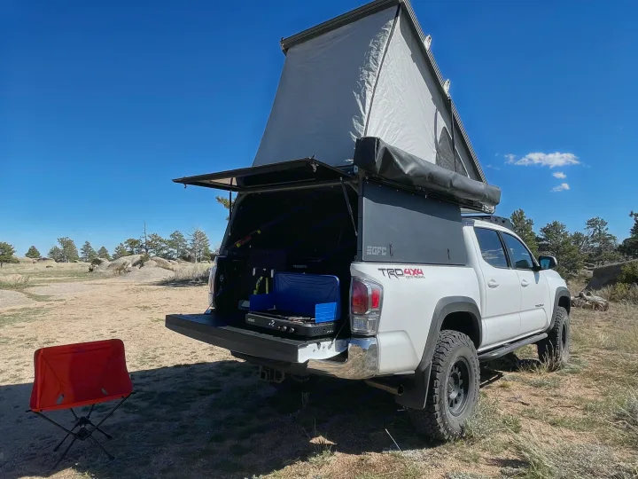 White Toyota Tacoma with Go Fast Camper and tailgate kitchen, ideal for an rv rental adventure in nature.. Toyota Tacoma TRD Off-Road 2023