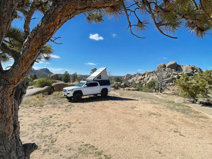 White overlanding truck with pop-top camper, ideal for an RV rental adventure in a stunning rocky landscape.. Toyota Tacoma TRD Off-Road 2023
