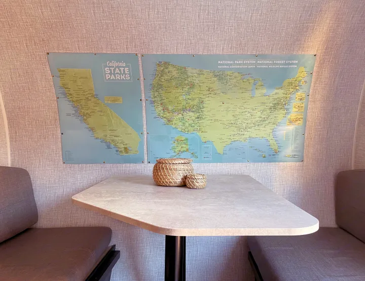 RV rental dining area featuring US National and CA State Park maps on the wall, with woven baskets on the table and comfy seating.. Braxton Creek Bushwhacker Plus 2022