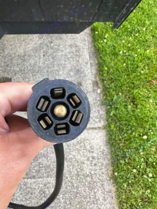A hand holds a 7-pin RV trailer electrical plug, essential for lights & brakes on your RV rental for safe towing.. Cherokee wolf pup 2021