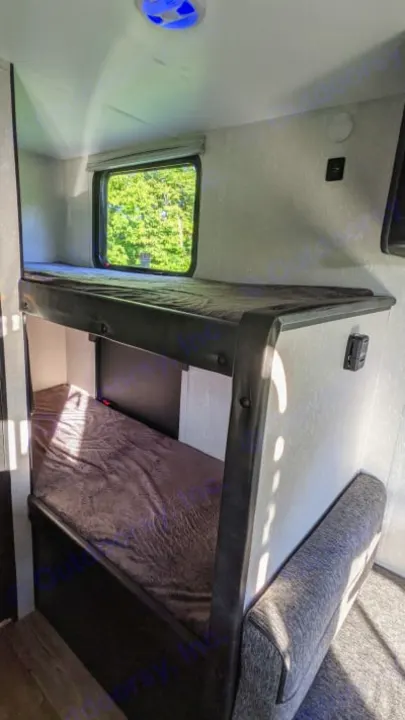 Compact RV rental interior featuring cozy bunk beds with a window view. Perfect for family camping adventures.. Cherokee wolf pup 2021