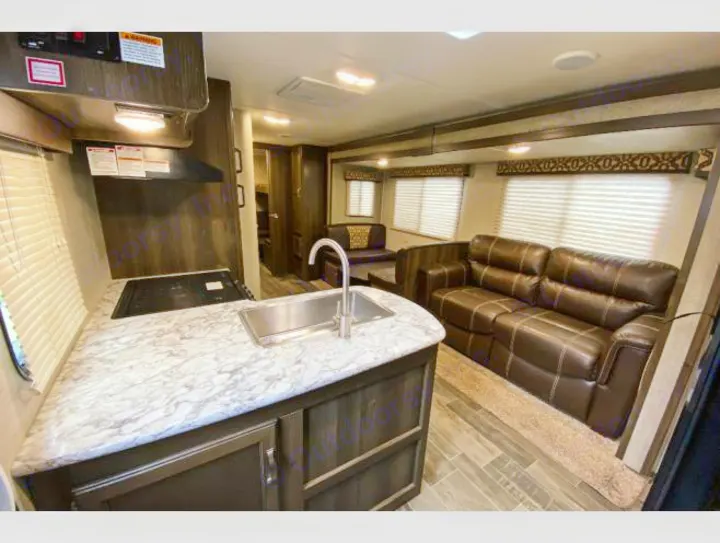 Explore this comfortable RV rental interior, featuring a well-equipped kitchen and a spacious living area with a cozy sofa.. Keystone RV Bullet Ultra Lite 2018