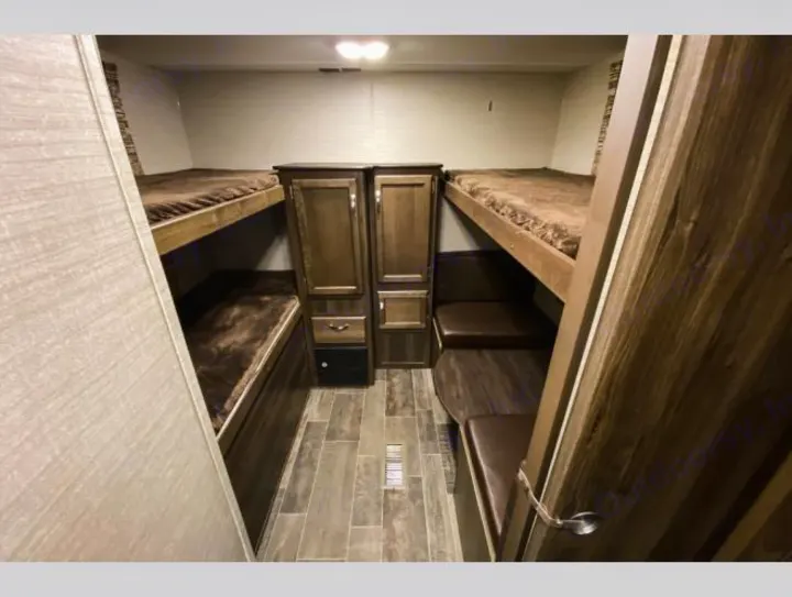 RV rental bunkhouse: Interior with stacked brown bunk beds on left and right, plus central storage.. Keystone RV Bullet Ultra Lite 2018