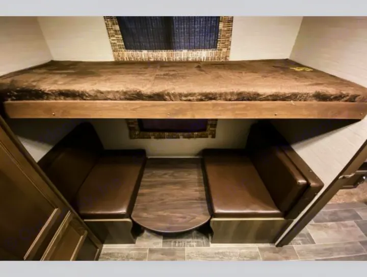 RV rental: Compact interior with a brown bunk bed above a dinette, featuring two cushioned benches and a table.. Keystone RV Bullet Ultra Lite 2018