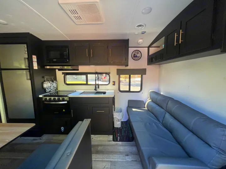 Spacious rv rental interior with full kitchen, sofa seating, and wood-look flooring, ready for camping adventures.. Keystone RV Springdale 2022
