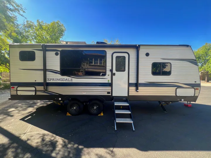 Light-colored Springdale travel trailer, a great option for an RV rental. Parked outdoors with steps extended.. Keystone RV Springdale 2022