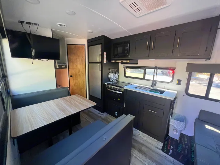 Modern RV rental interior: Full kitchen, cozy dinette, and TV. Ideal for comfortable road trips.. Keystone RV Springdale 2022