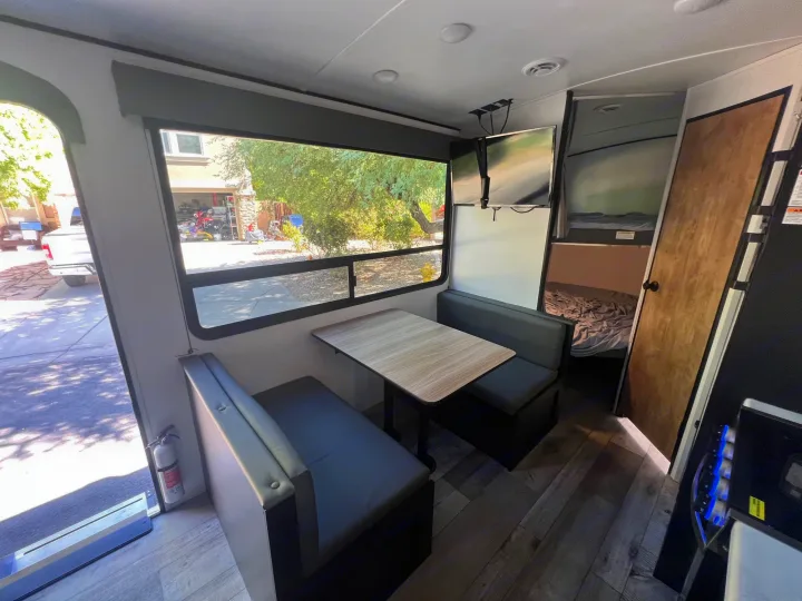 Explore this RV rental's dinette area, featuring spacious windows, dual TVs, and easy access to integrated bunk beds.. Keystone RV Springdale 2022