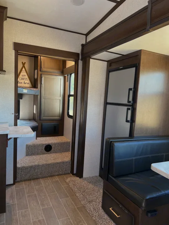 Cozy RV rental interior: modern dinette, fridge, and steps to comfy bunk beds for happy campers.. Atlas Atlas Fifth Wheel 2020