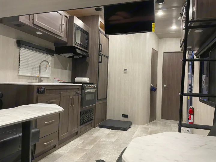 Inside a modern rv rental, featuring a full kitchen, dining area, and bunk beds, perfect for family adventures.. Genesis Supreme Rv Genesis Supreme 2022