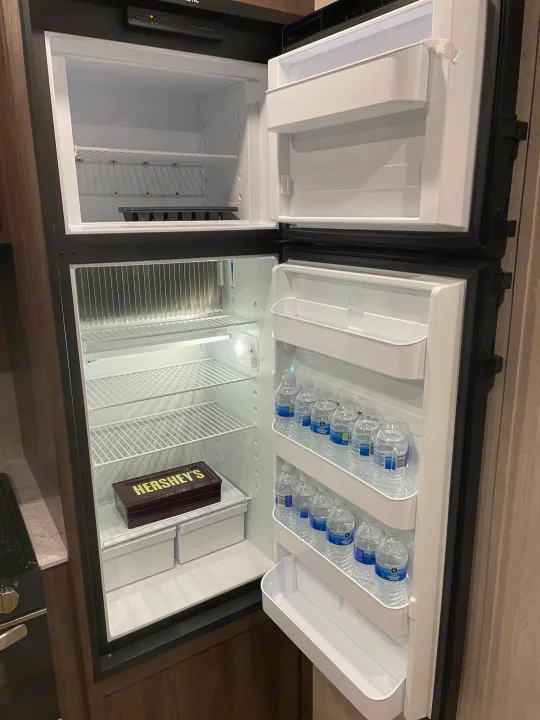Inside an RV rental, this clean fridge/freezer is pre-stocked with bottled water, ready for your trip's essentials.. Genesis Supreme Rv Genesis Supreme 2022