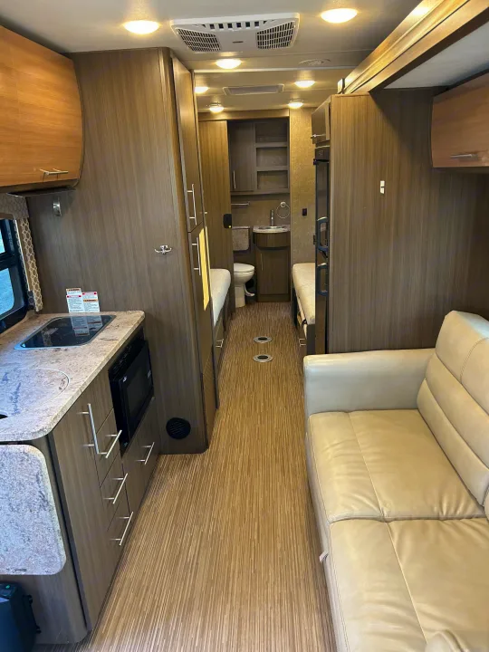 Inside a modern RV rental: well-equipped kitchen, compact bathroom, comfy sofa, and twin sleeping spaces.. Thor Axis 2018