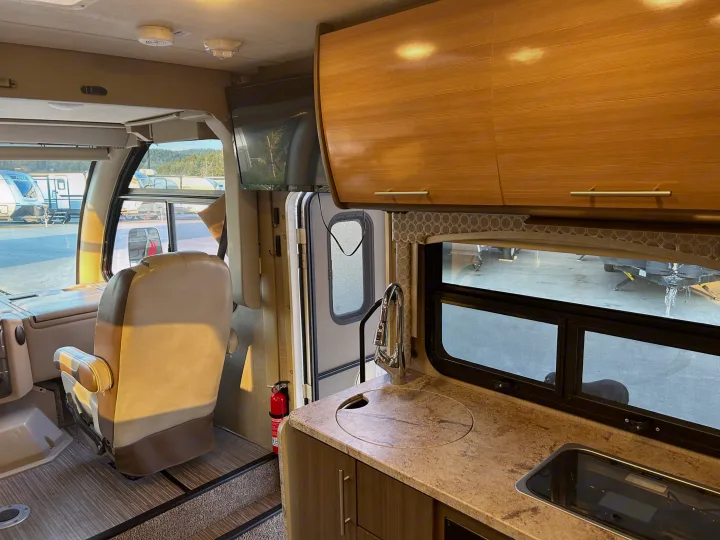 Spacious RV rental interior featuring a functional kitchen, comfortable living area, and a view of the lot.. Thor Axis 2018