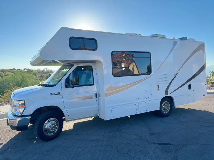 White RV rental, a bright Class C motorhome on a sunny day. Parked on asphalt with clear blue sky, ready for adventure.. Thor Majestic 2019