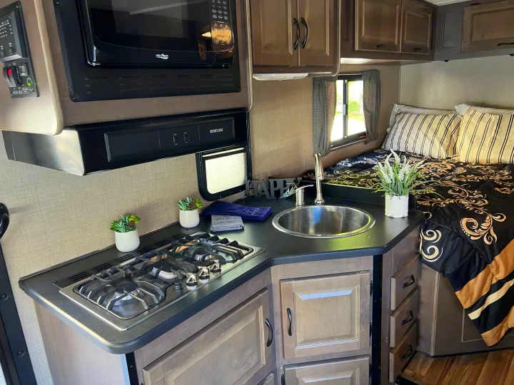 Step into this well-equipped rv rental featuring a kitchenette with stove, sink, microwave, and a comfy bed.. Thor Majestic 2019