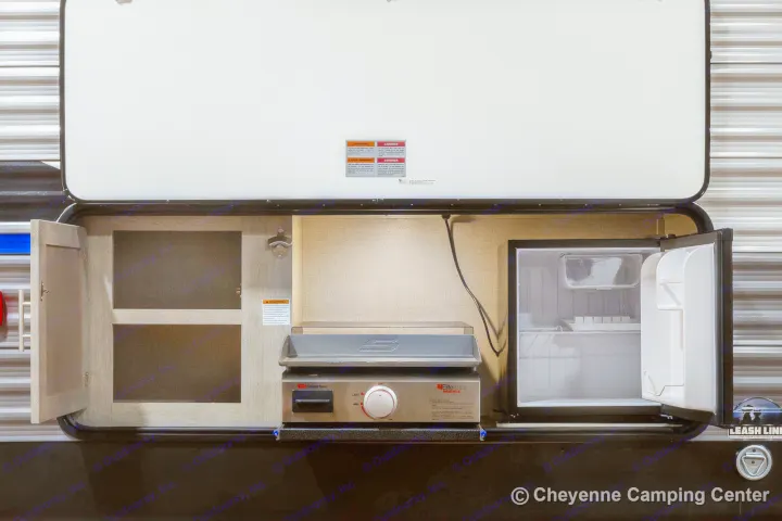 This rv rental features an outdoor kitchen with a griddle, mini-fridge, and storage, perfect for camping.. Coachmen Catalina 2022