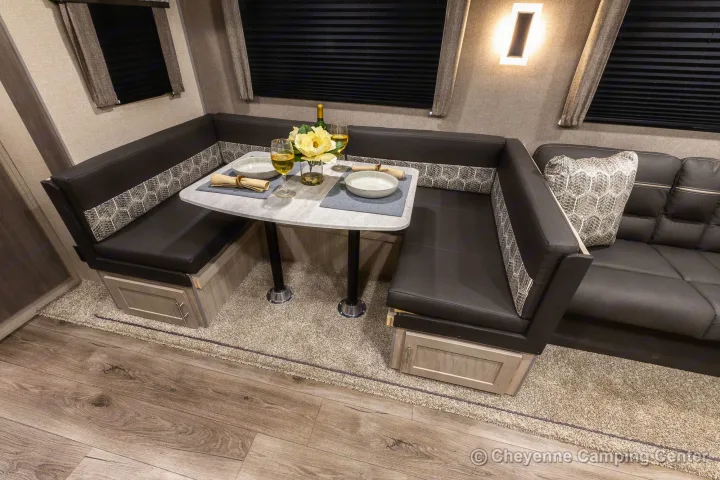 Modern RV rental interior: cozy dinette booth with set table, patterned cushions, and an adjacent sofa for relaxation.. Coachmen Catalina 2022