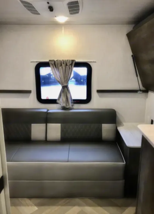 Modern RV rental interior with comfortable seating, a window with curtains, AC unit, and shelves. Perfect for your next adventure.. Forest River Salem Cruise Lite 2021