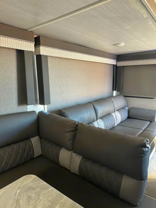 Modern RV rental interior: spacious L-shaped gray sofa with patterned accents, textured walls, and window blinds.. Forest River Salem Cruise Lite 2021