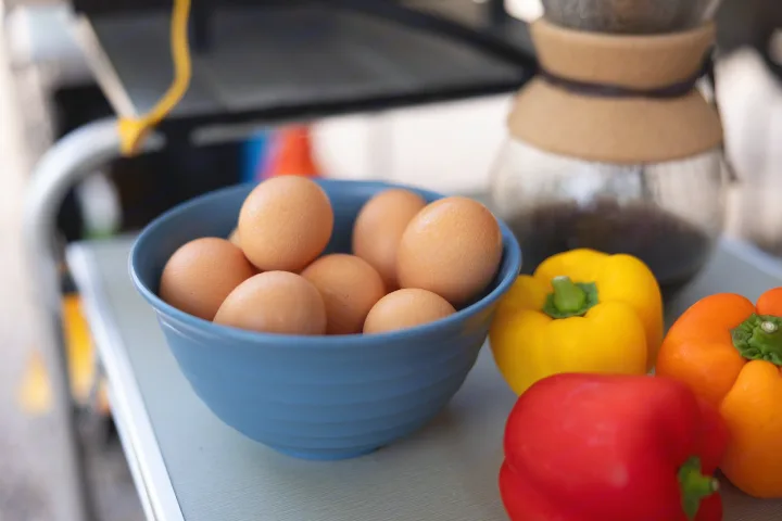 Fresh eggs, colorful bell peppers, and coffee on an RV rental table. Perfect for a delicious camping breakfast!. Ember Overland 2022