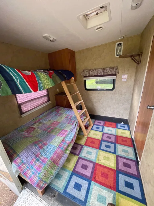 RV rental bunkhouse: bright, playful interior with colorful rug, bunk beds, ladder, window, and storage. Ideal for families.. Keystone RV Cougar 2012