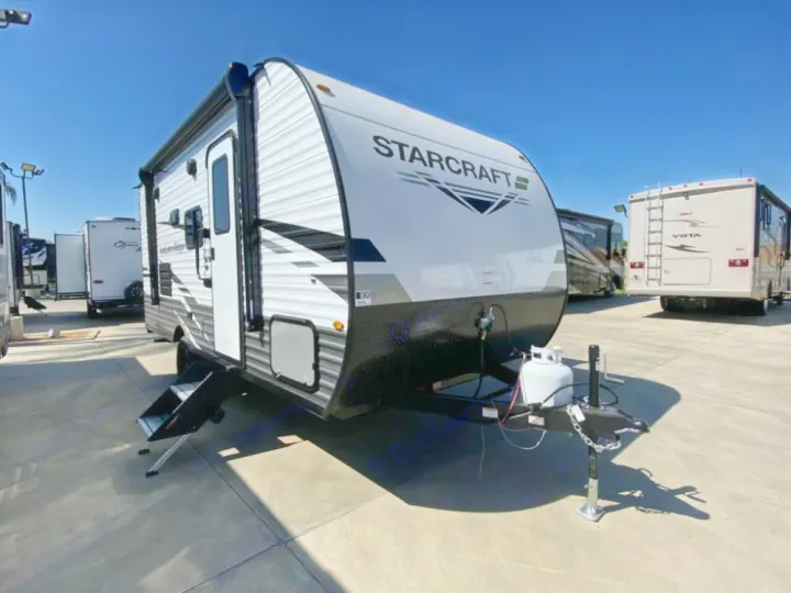 Explore the outdoors! This new white Starcraft travel trailer, perfect for your next RV rental adventure, is shown parked on concrete with blue sky.. Starcraft Autumn Ridge 2023