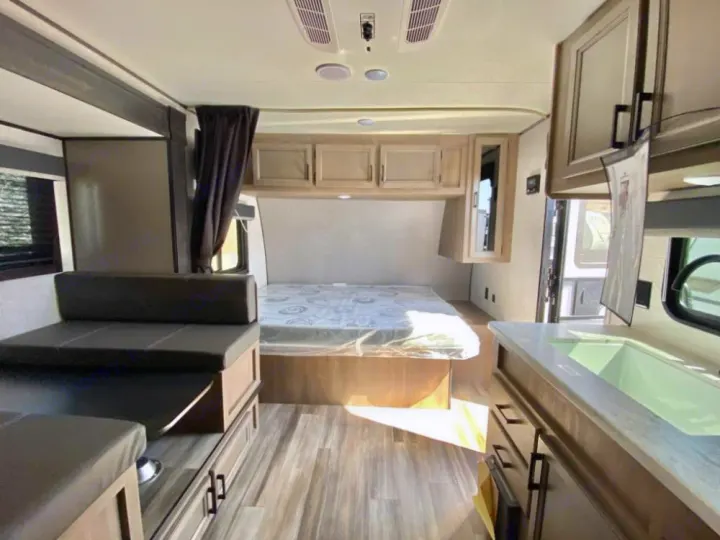 RV rental interior: cozy bed, bright kitchen with sink, and convertible dinette. Spacious and modern layout.. Starcraft Autumn Ridge 2023