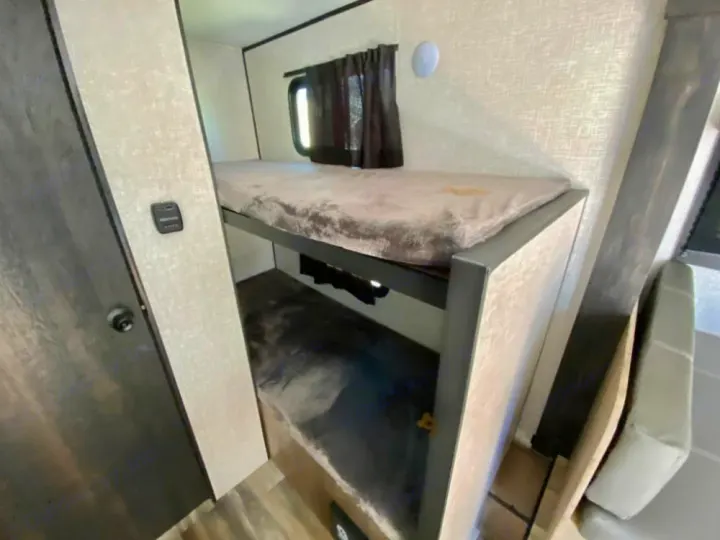 RV rental: Spacious bunk beds within the RV interior, featuring a window, light, and control panel on the wall.. Starcraft Autumn Ridge 2023