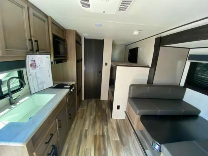 Bright RV rental interior with kitchen sink, stove, microwave, dinette, and bunk beds.. Starcraft Autumn Ridge 2023