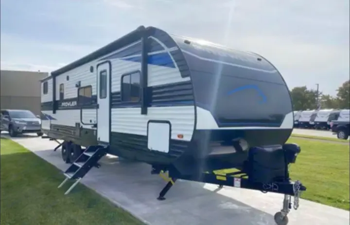 Sleek black, white, and blue travel trailer with awning and steps down, perfect for your next rv rental adventure.. Heartland RVs Prowler 2022