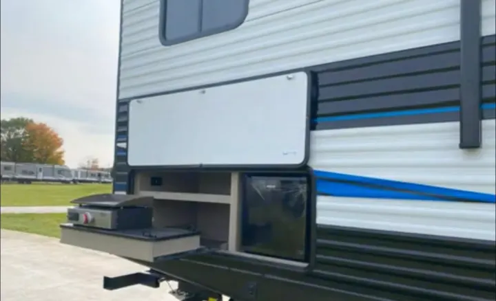 Explore the convenience of this RV rental's outdoor kitchen, featuring a pull-out griddle and compact refrigerator.. Heartland RVs Prowler 2022