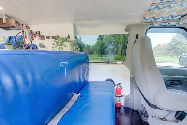RV rental interior with blue seating, electrical components, fire extinguisher, and a park view from the window.. Ford Ford E350 2007