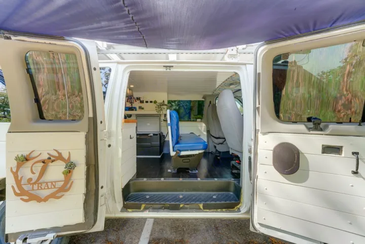 Inside this custom RV rental van conversion: a cozy interior with a blue seat, storage, and personalized decor.. Ford Ford E350 2007
