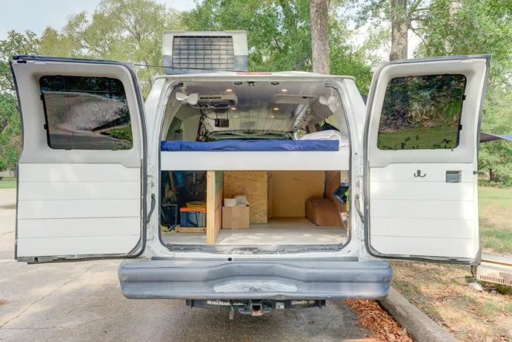 Explore this RV rental: A white van converted for camping, featuring a raised bed, storage, and ceiling fans.. Ford Ford E350 2007