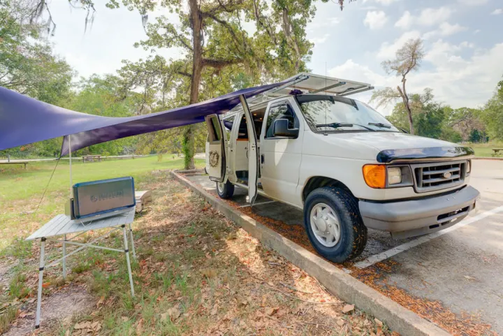 RV rental ready: white camper van with extended awning, roof solar panels, and outdoor table with power unit.. Ford Ford E350 2007