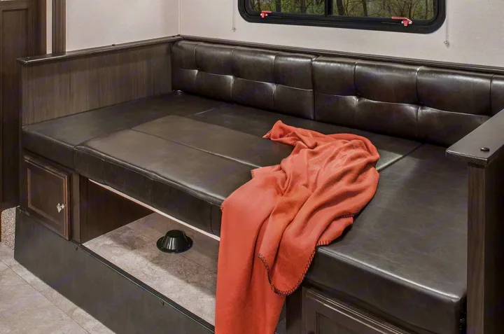 RV rental interior features a durable dark upholstered dinette bench with storage, a peach blanket, and window.. Sonic Sonic Trailer 2019