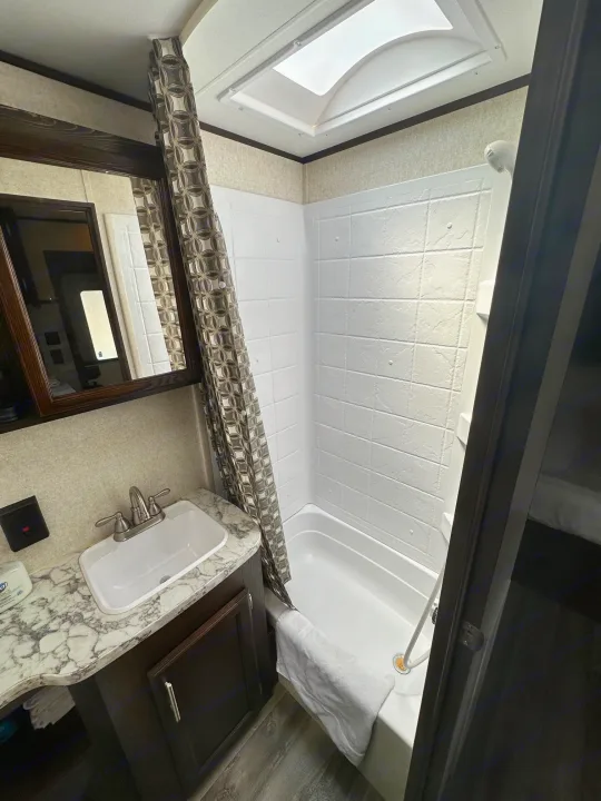 RV rental bathroom features a sink, mirror, shower/tub with curtain, and a skylight for natural light.. Jayco Jay Flight SLX 2020