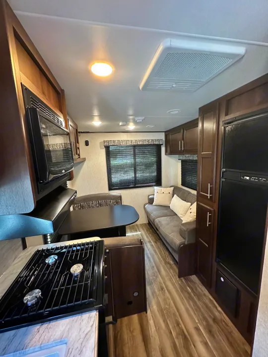 Inside an RV rental: modern kitchen, dining booth, and sofa offer compact comfort for travel adventures.. Jayco Jay Flight SLX 2020