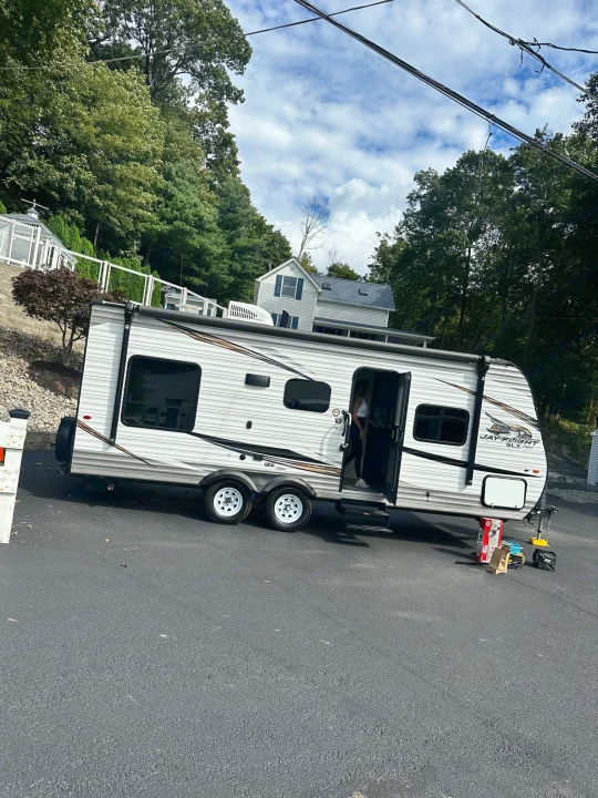 White Jayco Jay Flight travel trailer (RV rental) parked on asphalt. Person at open door.. Jayco Jay Flight SLX 2020