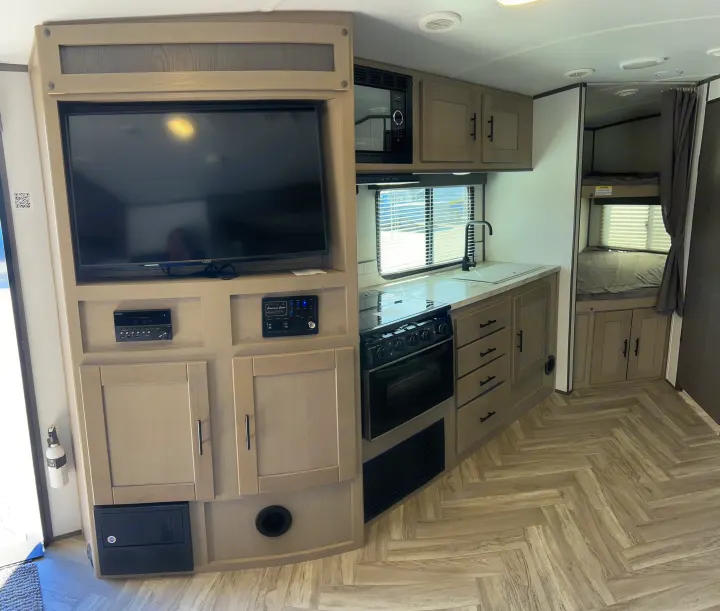 Spacious rv rental interior with a modern kitchen (stove, microwave, sink), entertainment center with TV, and bunk beds visible.. Cruiser Rv Corp Shadow Cruiser 259BHS 2021