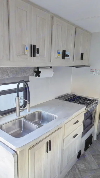 RV rental kitchen: light wood cabinets, modern countertops, double sink, and stove/oven setup for journeys.. Forest River Sunseeker LE 2022